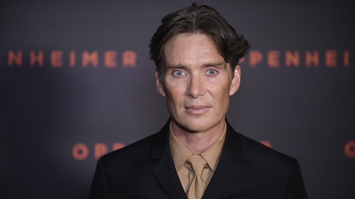 Cillian Murphy in a tan shirt and tie and dark jacket on the carpet for 'Oppenheimer'