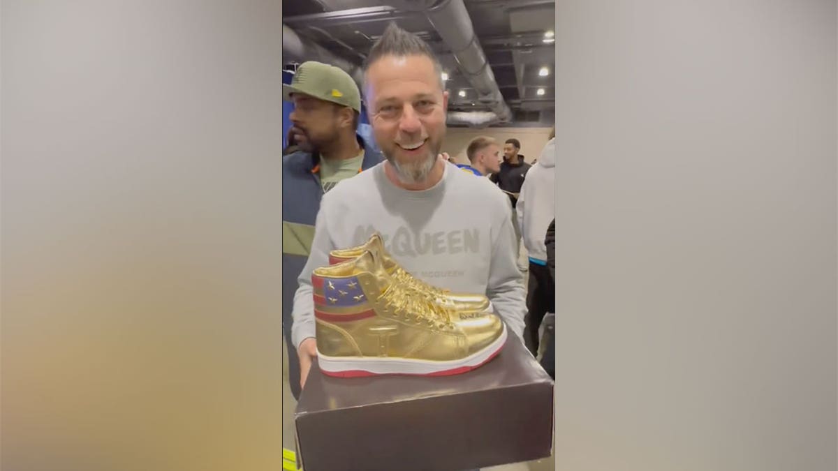 CEO Roman Sharf holds golden Donald Trump sneakers