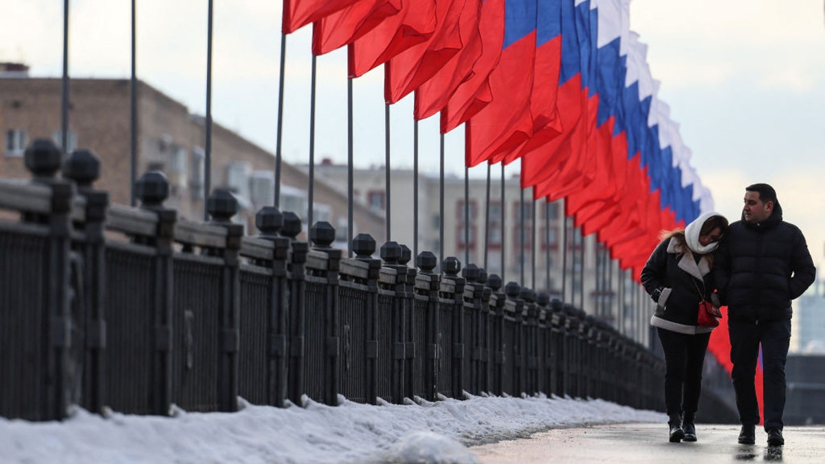 A couple walking by Russian flags