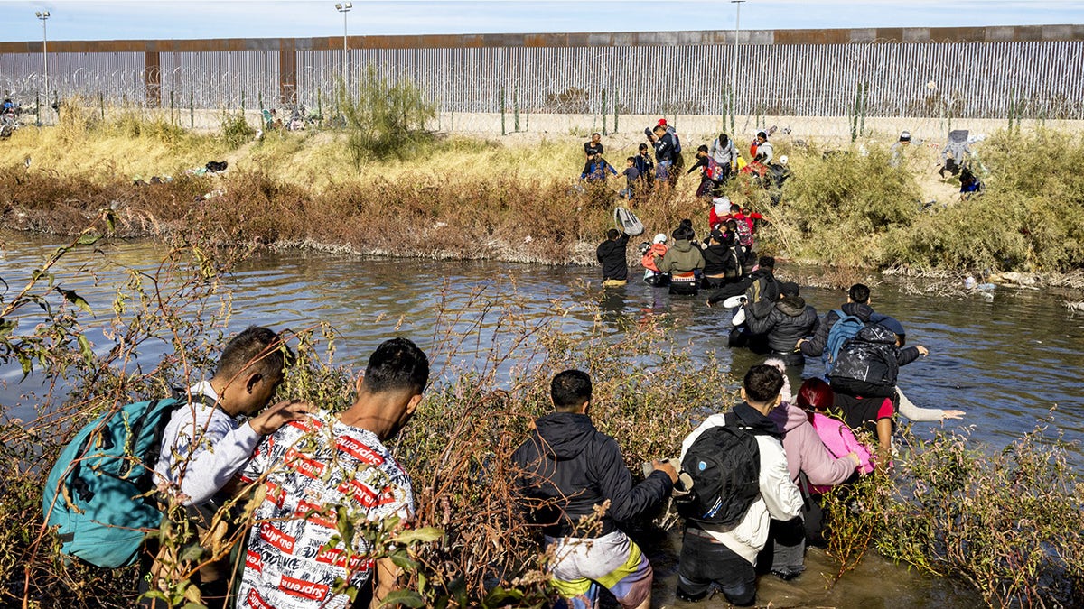 Hundreds of migrants, predominantly from Venezuela, cross the Rio Grande with the intention of seeking humanitarian asylum by crossing the border between Mexico and the United States in Ciudad Juarez, Mexico on December 05, 2023. Upon reaching the Rio Grande, they encountered a barrier of barbed wire and Texas National Guard soldiers prohibiting them from crossing the river. Nevertheless, many found a way to cross the river and formed a line in front of a gate in the wall marked with the number 36, hoping to be processed by the Border Patrol and subsequently apply for humanitarian asylum. (Photo by David Peinado/Anadolu via Getty Images)