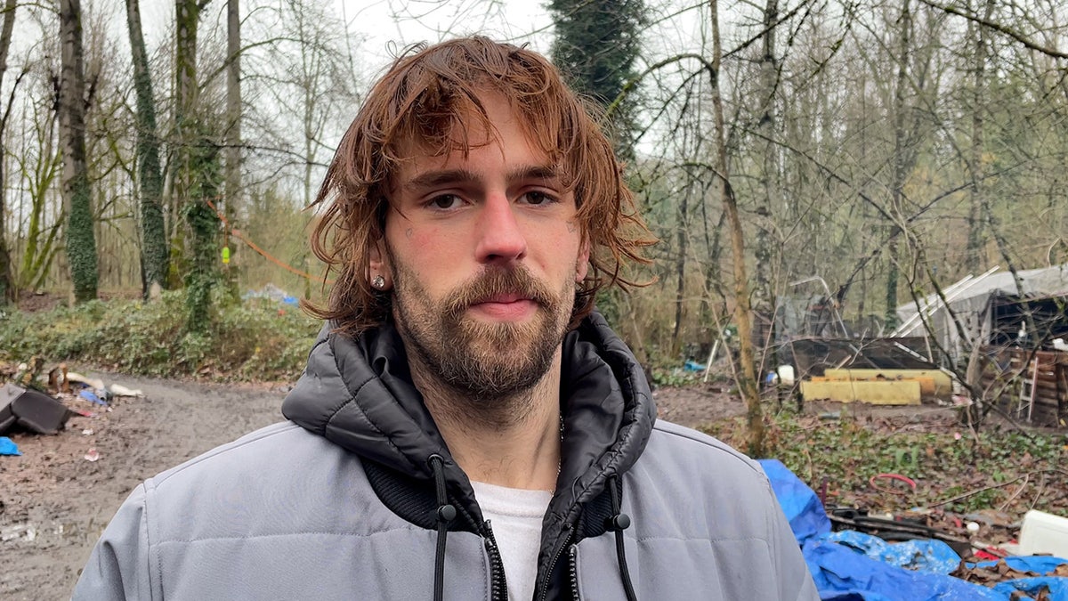 Hombre con chaqueta gris en un campamento de indigentes