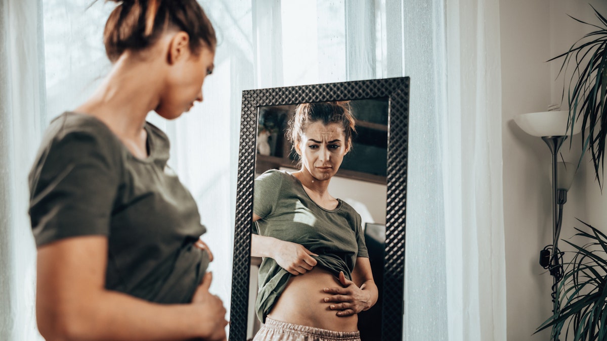 Woman bloated at mirror