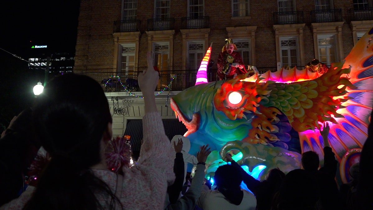 A woman is seen pointing at a float as it rolls on the streets of New Orleans.