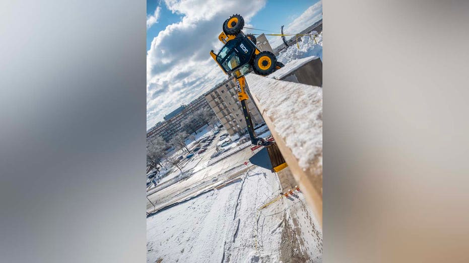 Video shows heavy equipment dangling off Wisconsin parking garage after it tipped over while clearing snow
