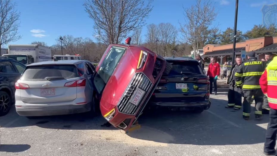 Driver rescued after car wedged between two vehicles in parking lot crash