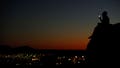 A young couple look at their phone as they sit on a hillside after sun set in El Paso, Texas, on June 20, 2018.