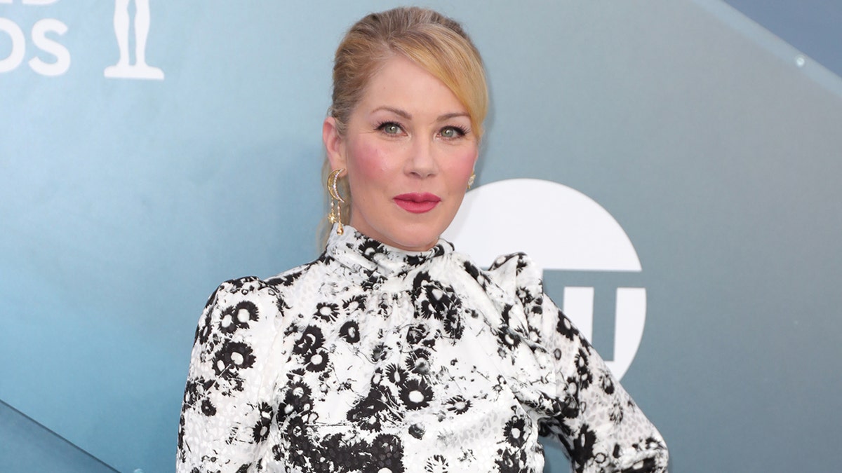 Christina Applegate wearing a white dress on the red carpet.