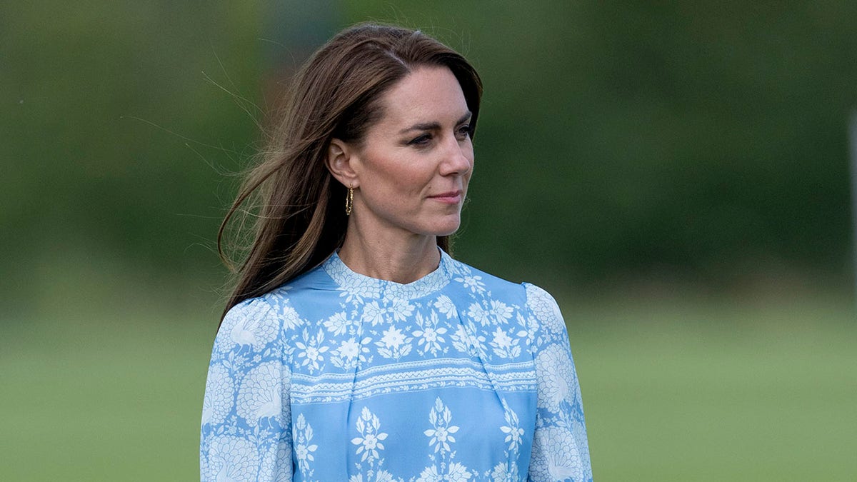 Kate Middleton standing in a field in a blue and white dress