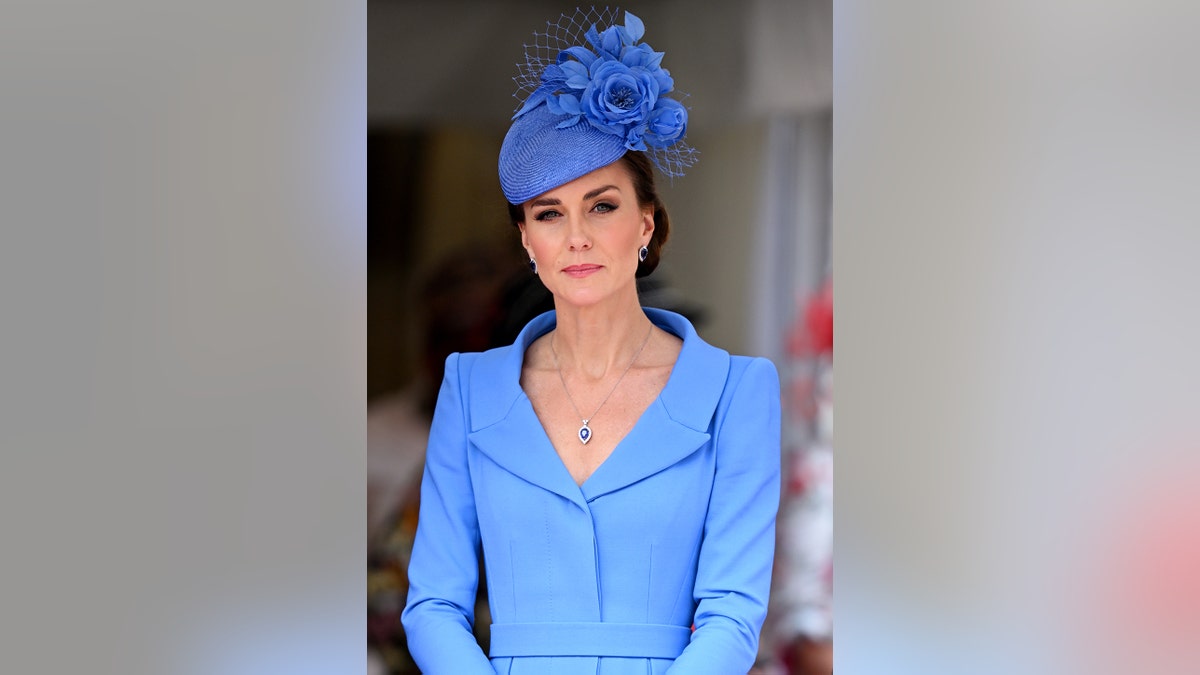 Kate Middleton looking serious in a periwinkle dress with a matching fascinator