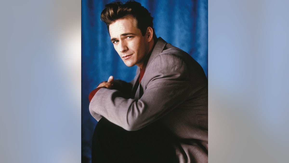Luke Perry in a blazer looking from the side