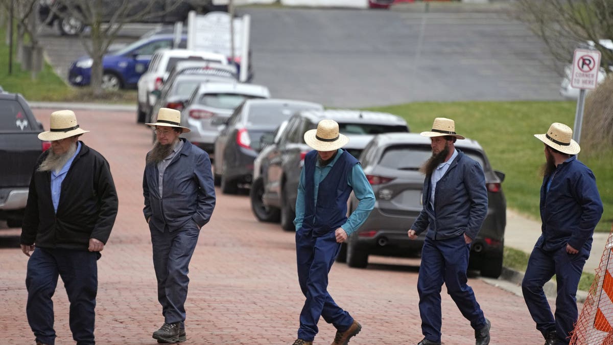 A group of Amish men crosses brick road to pennslyvania courthouse