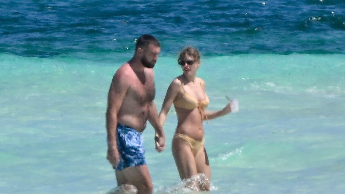 taylor swift and travis kelce walking in the waves