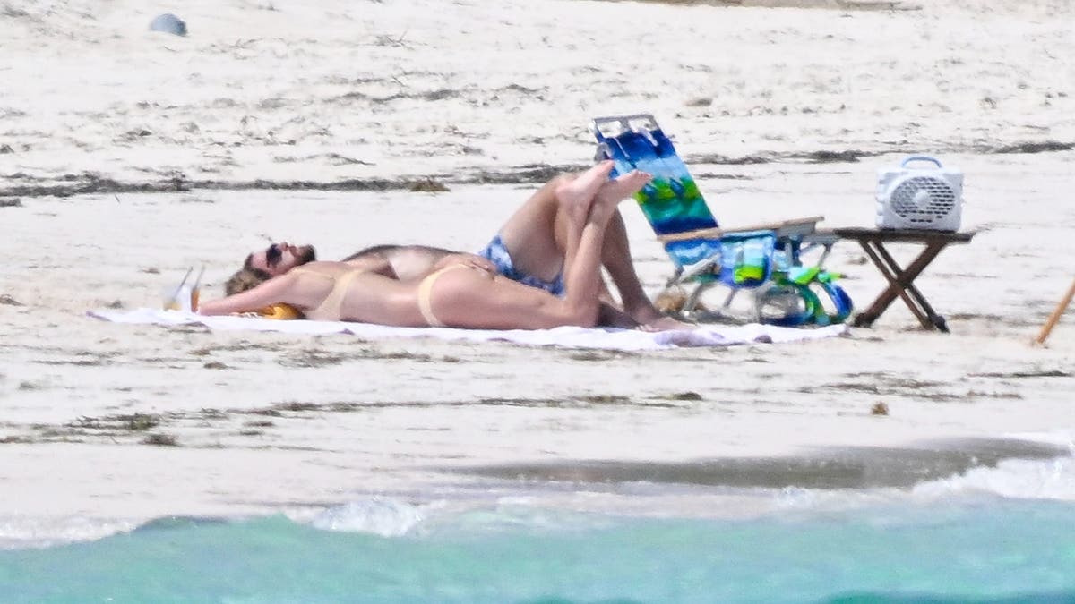 Travis e Taylor tomando banho de sol na praia