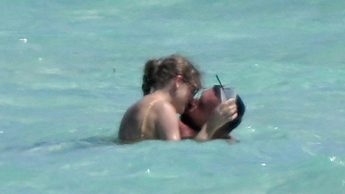 Travis Kelce e Taylor Swift se beijando no oceano