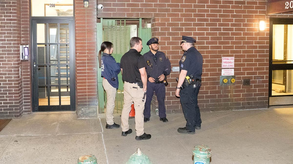 Police stand outside of the apartment building where the body of a woman was found stuffed in a dufflebag