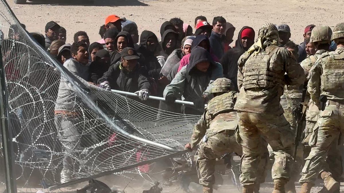 Migrants pulling at fencing at border gate in El Paso, Texas