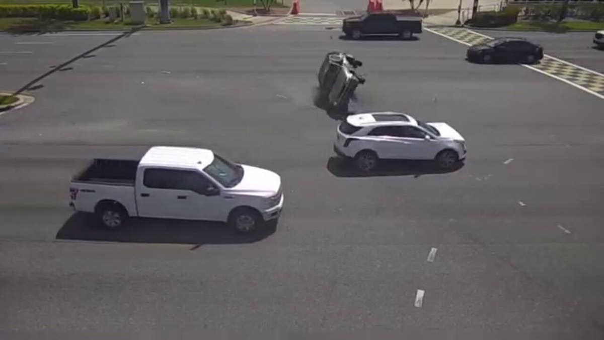 Group of people help flip over car on intersection