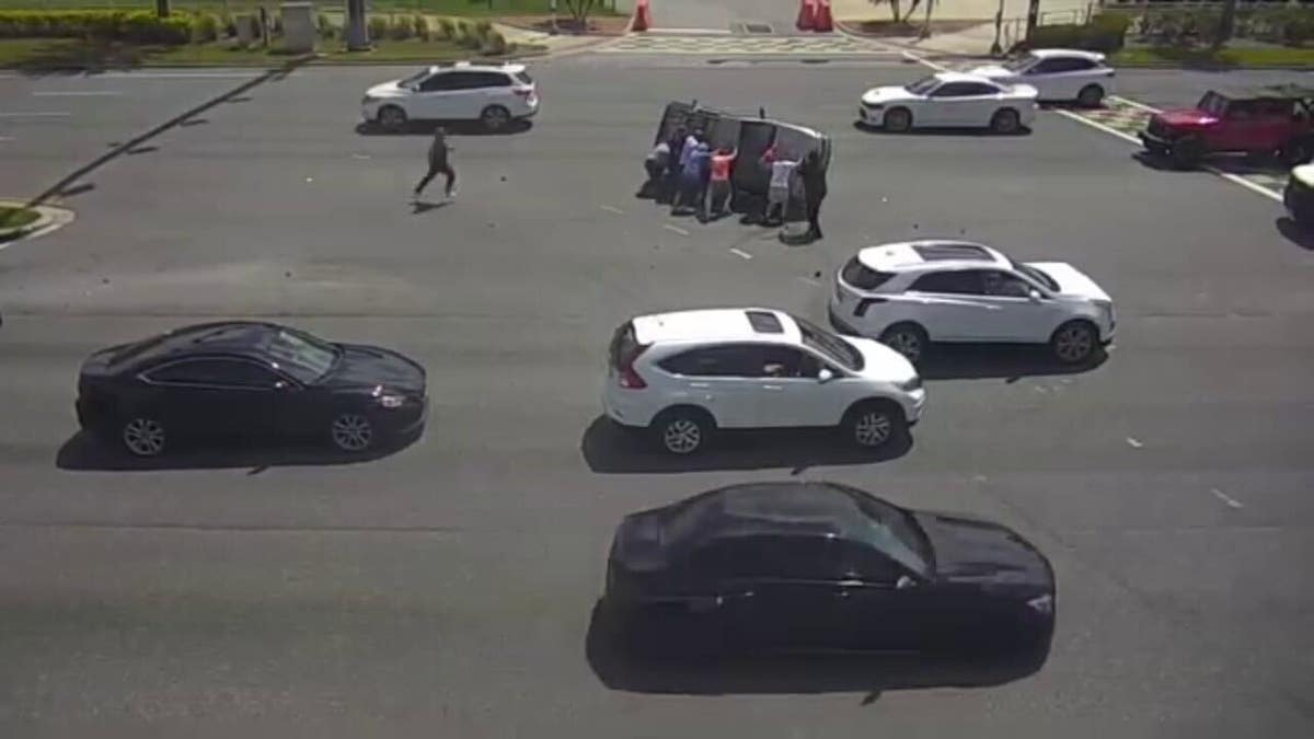 Group of people help flip over car on intersection