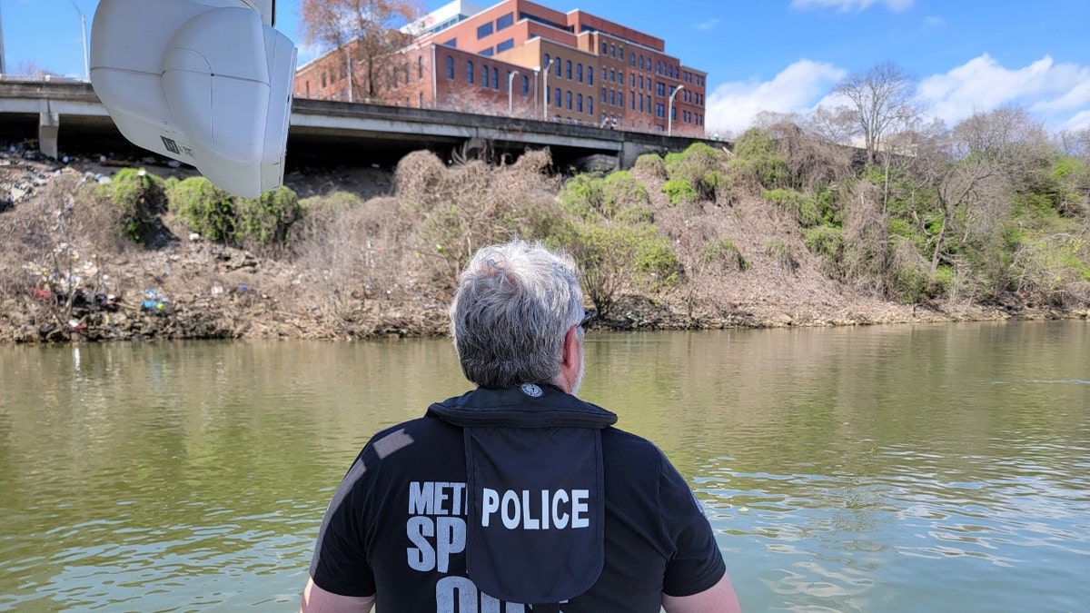 A Nashville police officer overlooks the Cumerland River while searching for Riley Strain