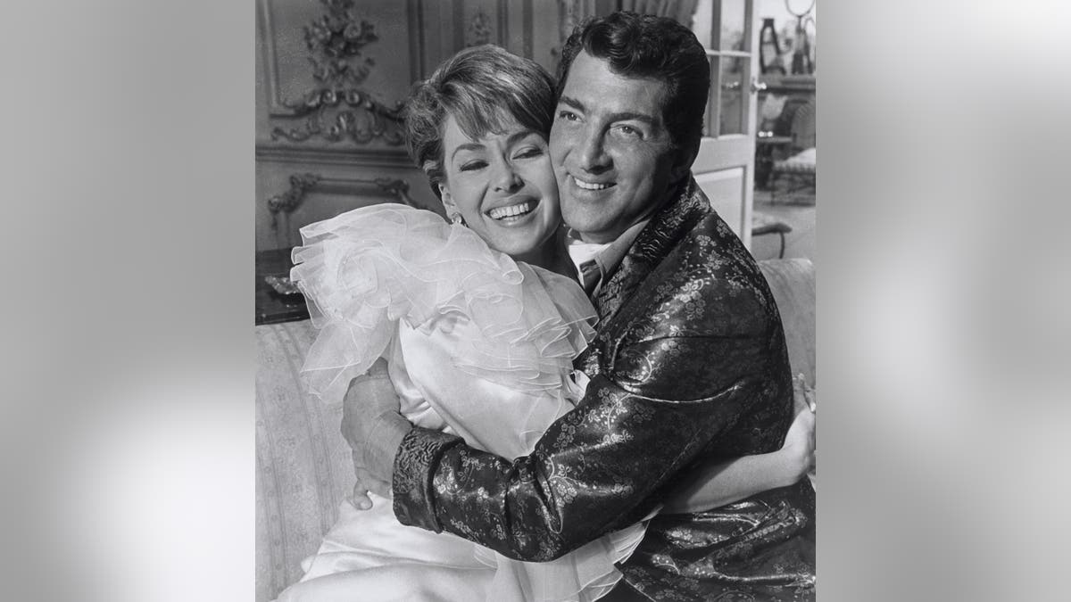 Dean Martin e Barbara Rush se abraçando e sorrindo no set.
