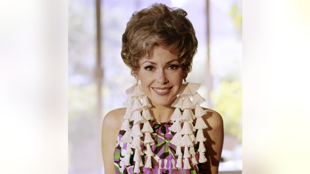 Barbara Rush smiling wearing colorful dress .