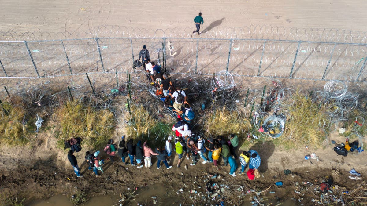 In an aerial view, immigrants pass through coils of razor wire while crossing the U.S.-Mexico border on March 13, 2024, in El Paso, Texas. (Photo by John Moore/Getty Images)