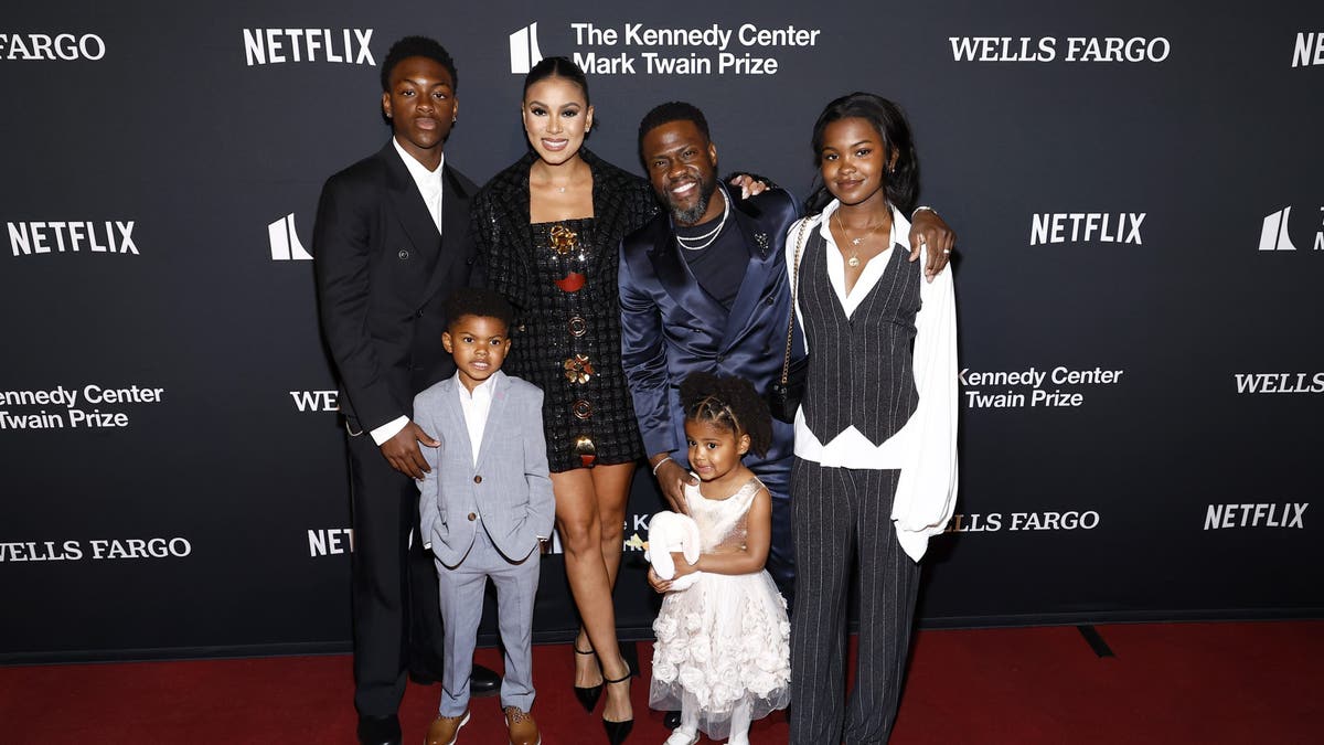 Kevin Hart and his wife, two daughters and two sons on a red carpet.