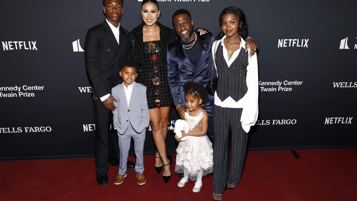 Kevin Hart and his wife, two daughters and two sons on a red carpet.