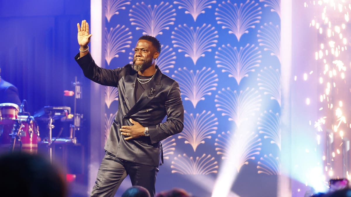 Kevin Hart standing on stage waving at crowd.