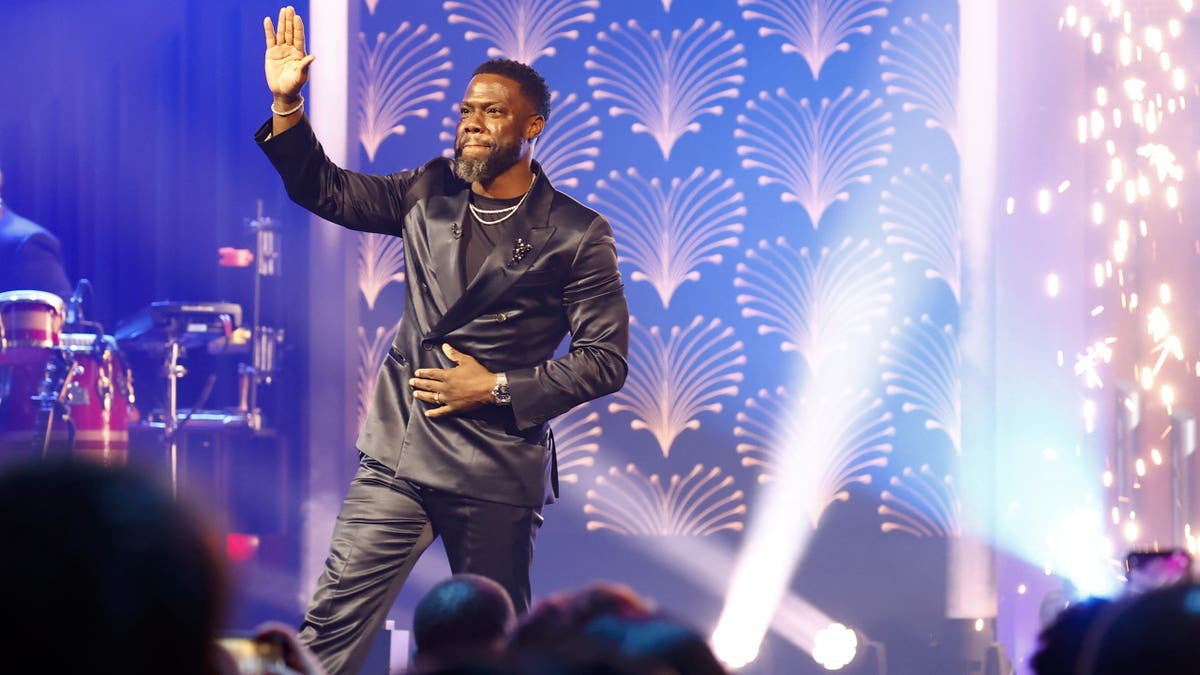 Kevin Hart standing on stage waving at crowd.