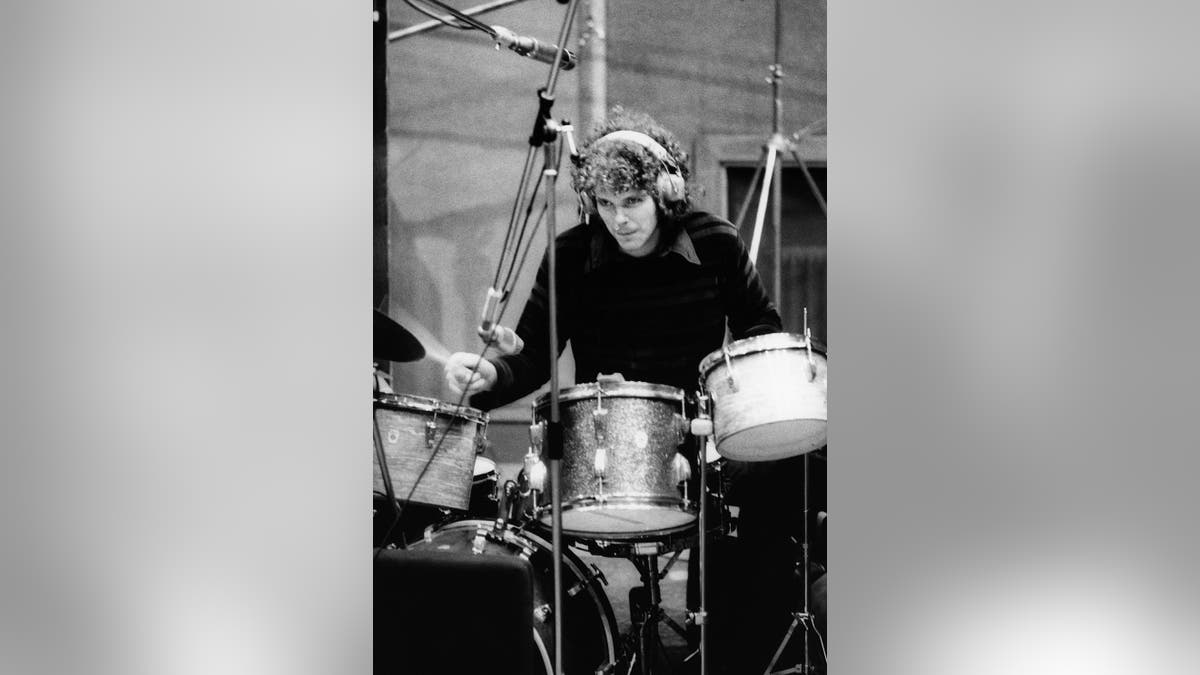 Jim Gordon usando fones de ouvido e tocando bateria