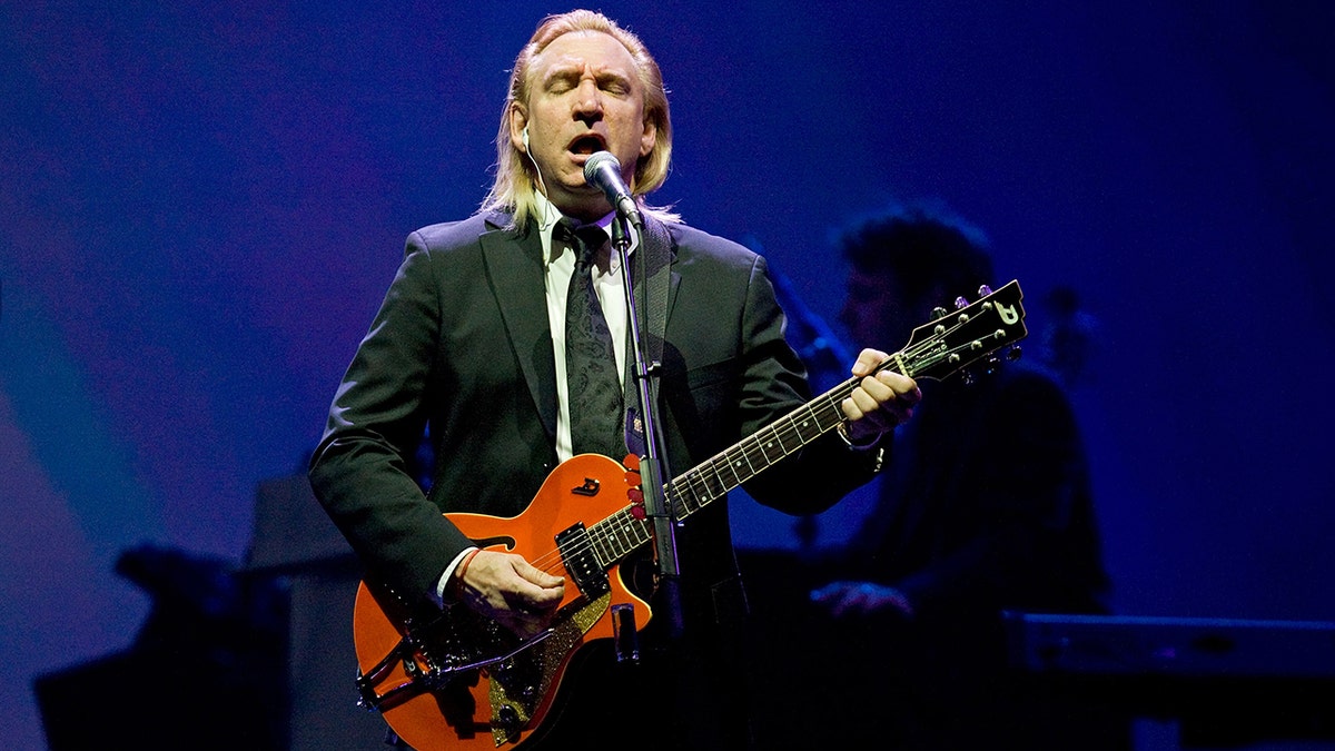 Joe Walsh in a suit performing on stage