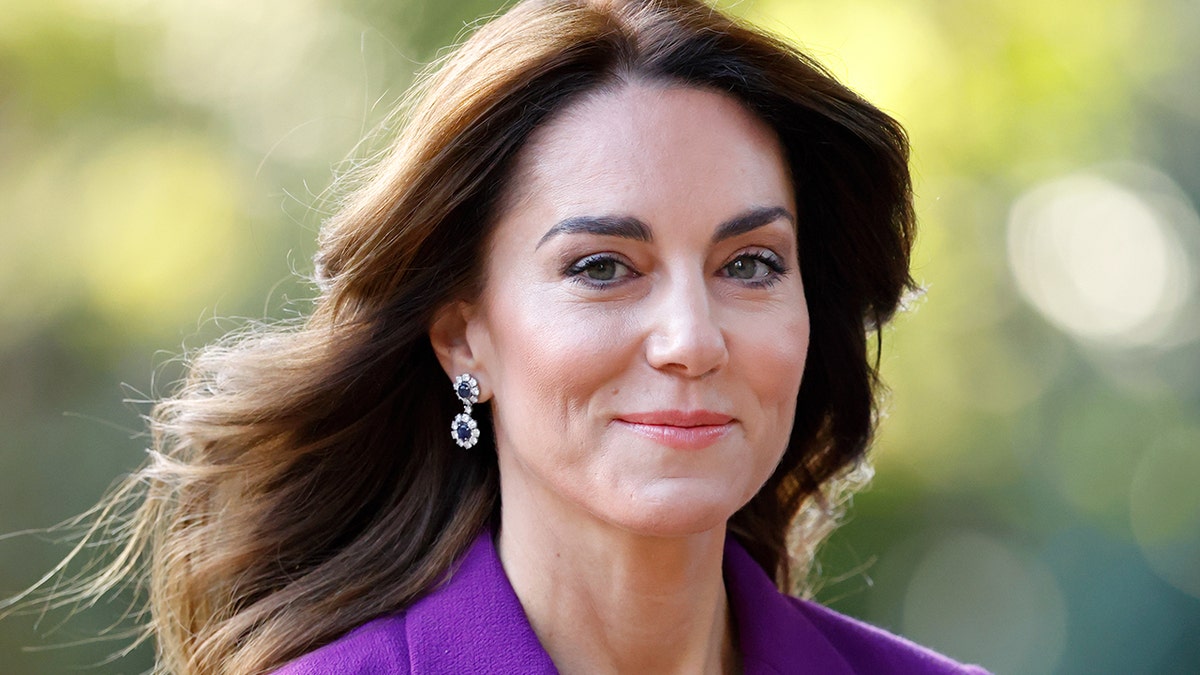 Kate Middleton smirking in a purple suit