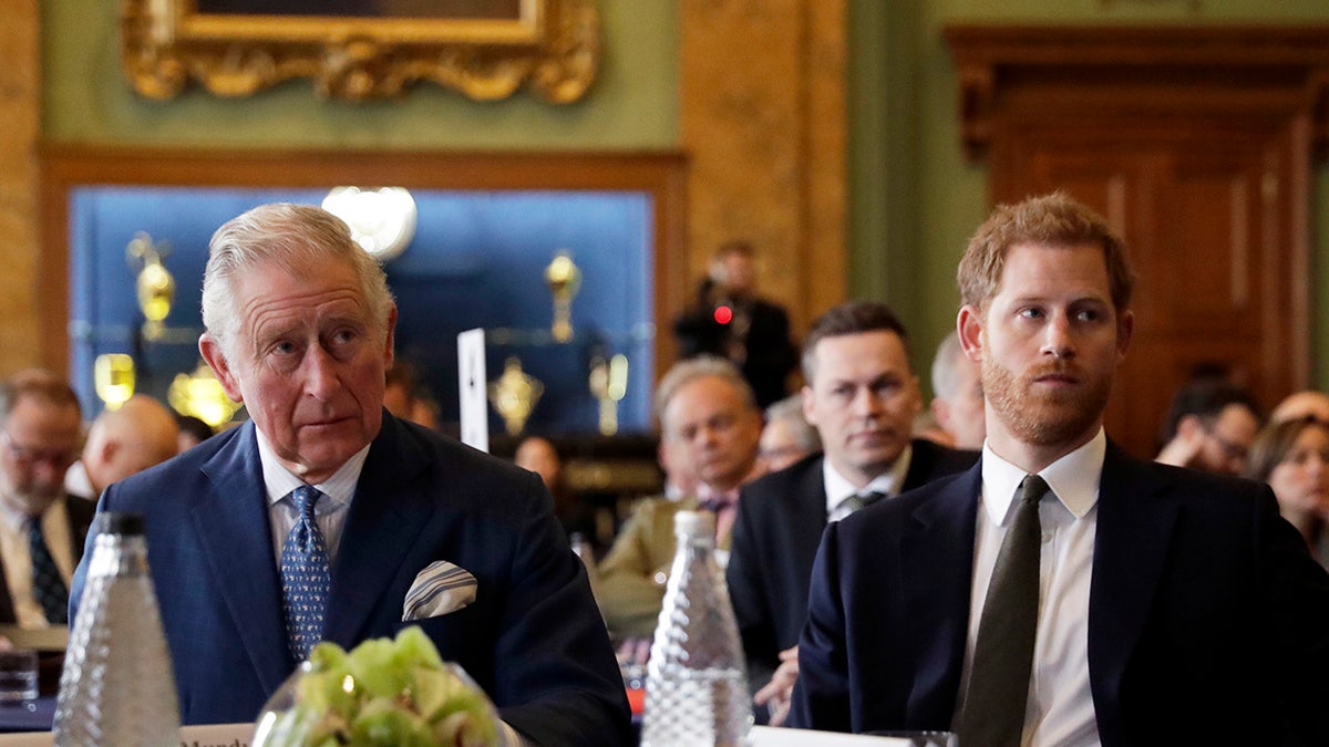 King Charles sitting next to Prince Harry as they both look serious