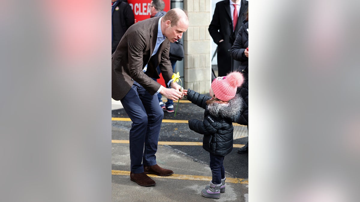 A little girl gives Prince William a daffodil