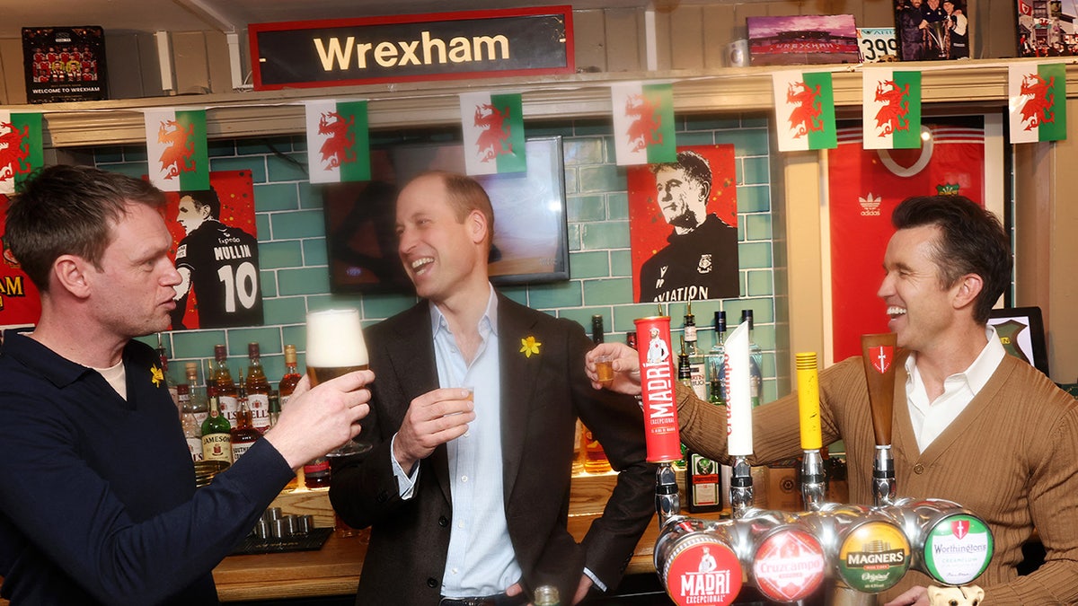 Prince William smiling and holding his shot