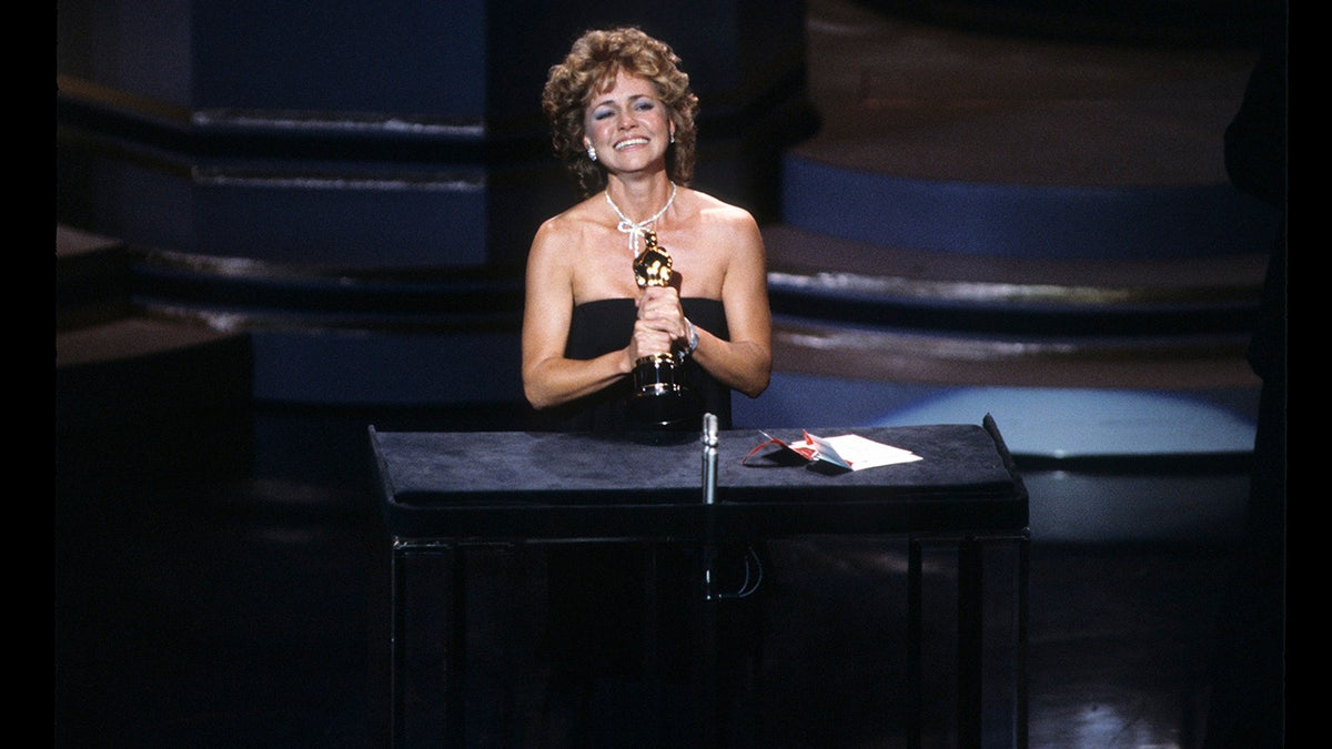 Sally Field on stage holding onto her Oscar