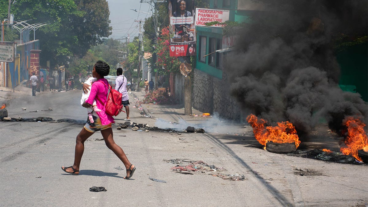 Woman carrying young child runs for safety in Haiti