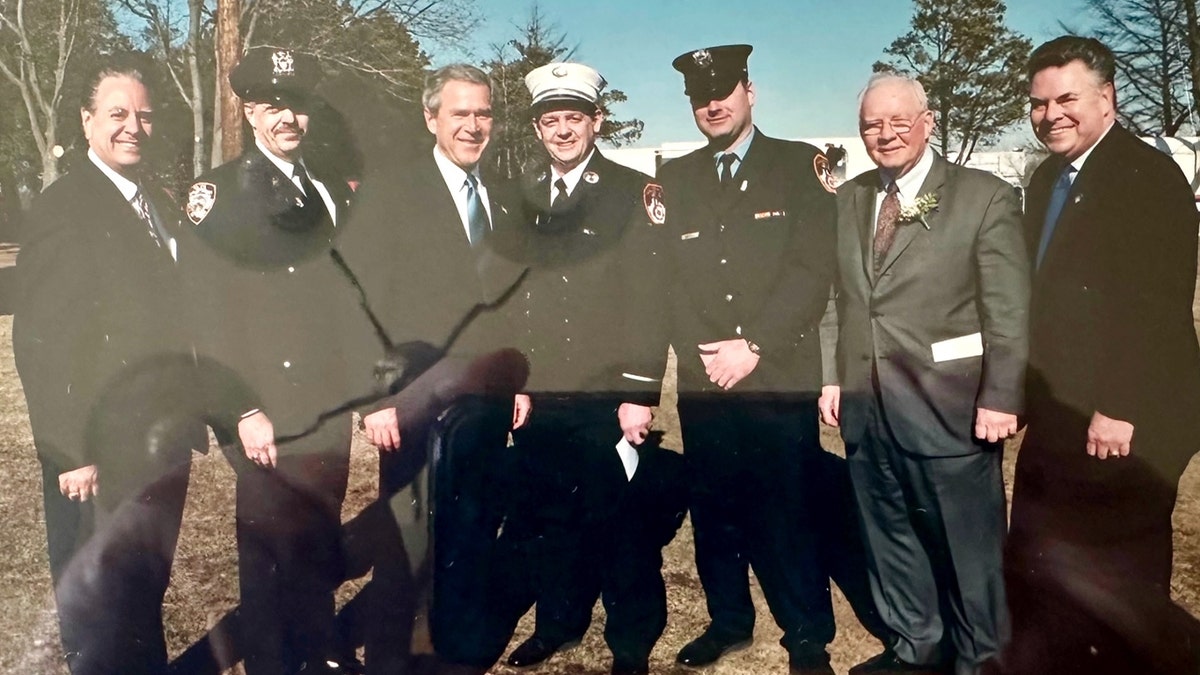Bombeiros e policiais uniformizados se reúnem com o então presidente George W Bush e o então deputado dos EUA Peter King