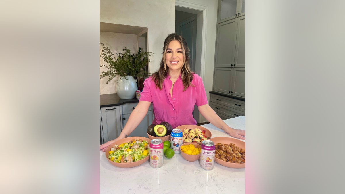 Jessie James Decker posing in kitchen with Waterloo Sparkling Water cans and recipes
