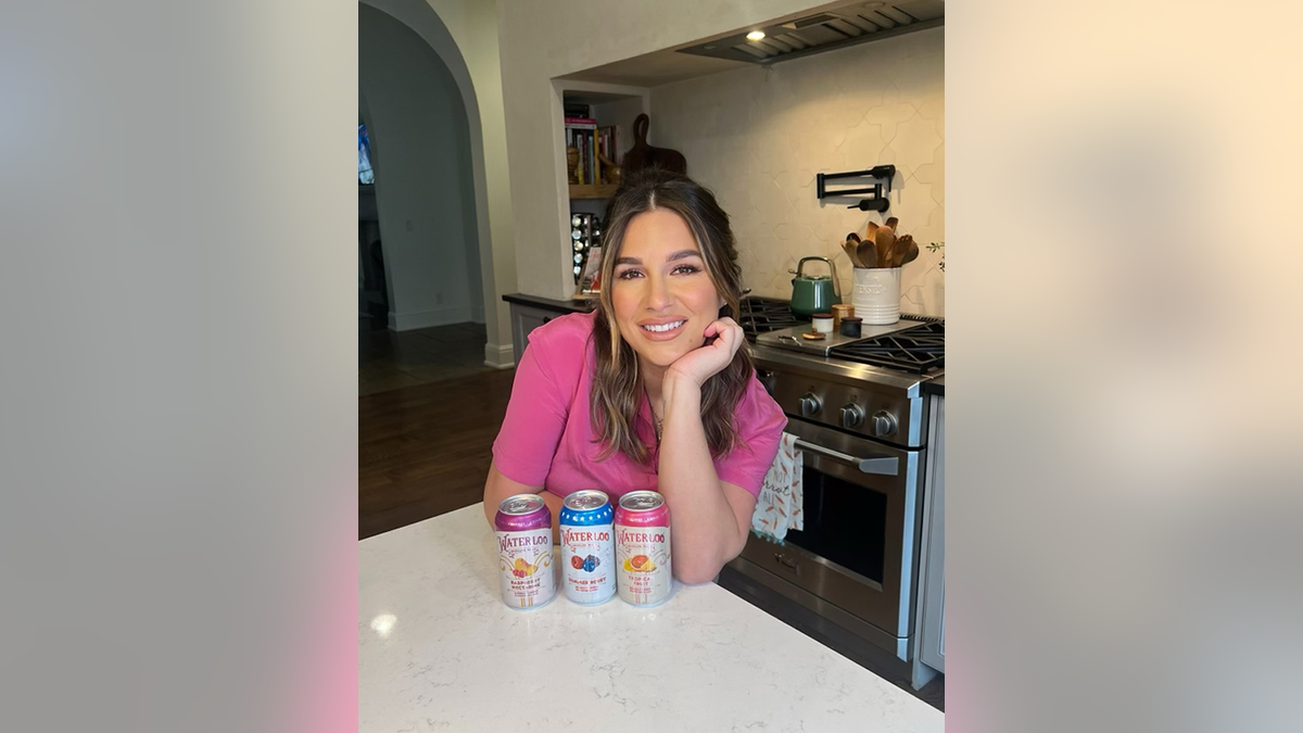 Jessie James Decker posing with Waterloo Sparkling Water cans in her kitchen