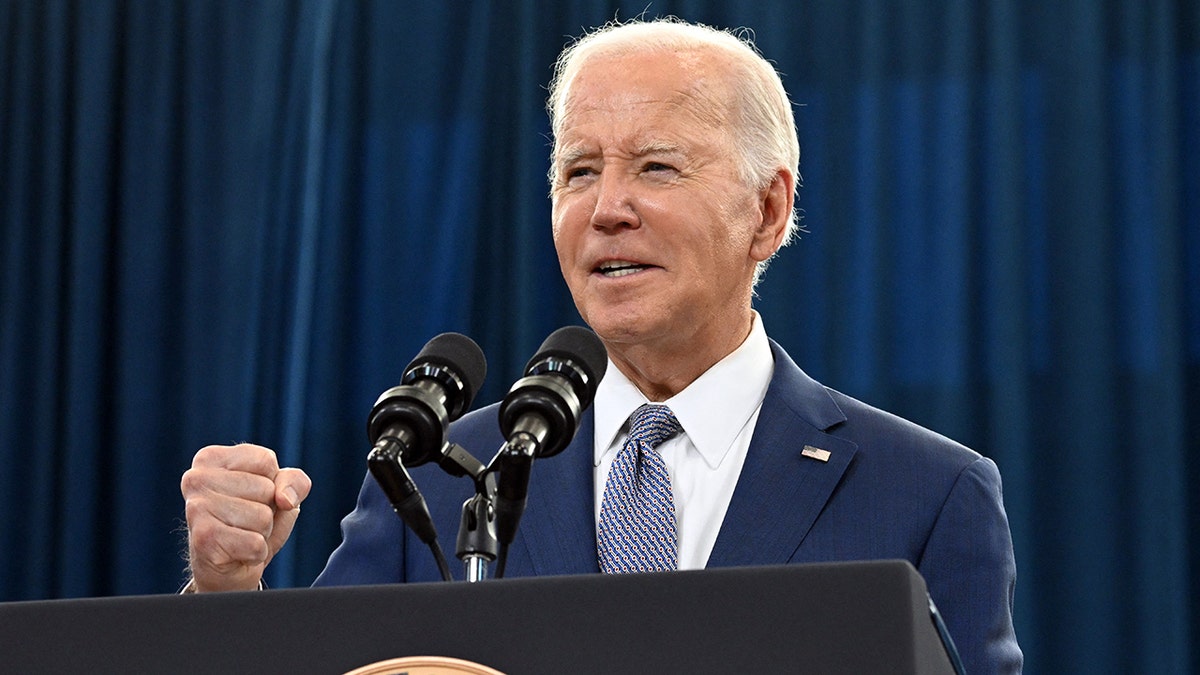 Joe Biden talking astatine  podium, making a fist