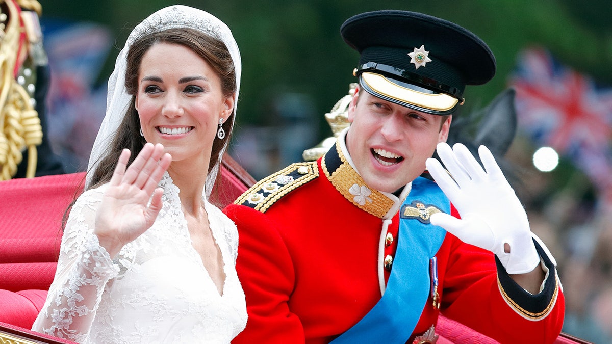 Kate Middleton waving from a carriage on her wedding day to Prince William who ls looking on in his red suit with his black cap
