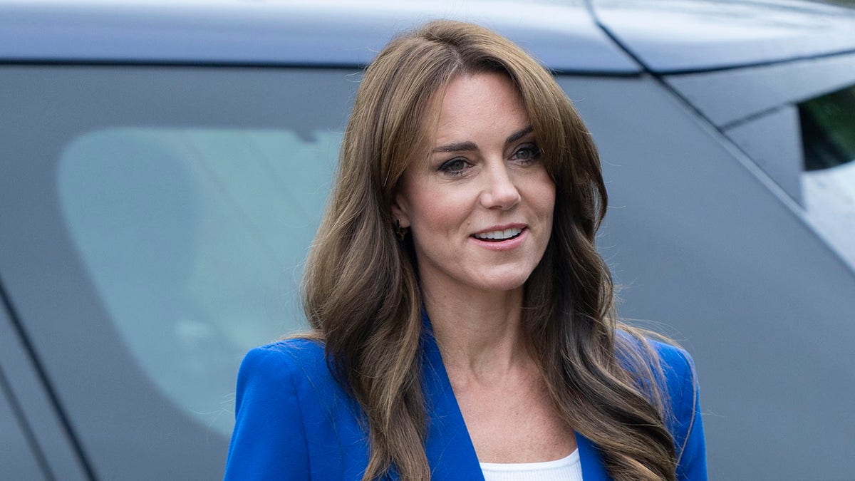 Kate Middleton standing in front of a car in a blue blazer
