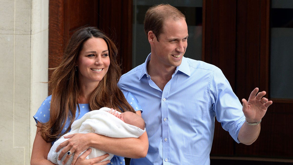 Kate Middleton segurando o bebê Príncipe George, com o Príncipe William ao seu lado.