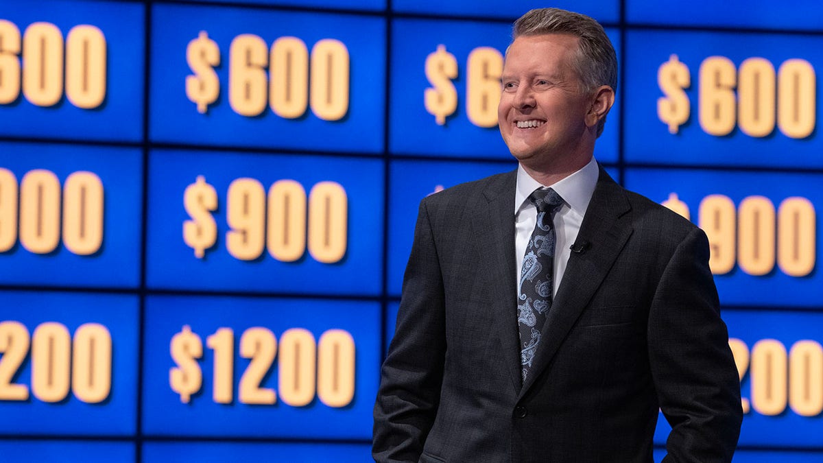 Ken Jennings em frente a uma parede de pistas do Jeopardy