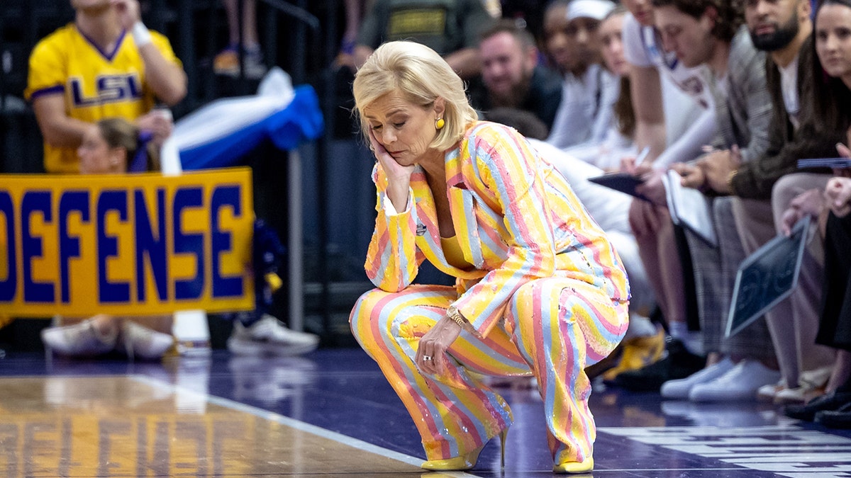Kim Mulkey crouched down with hand on head