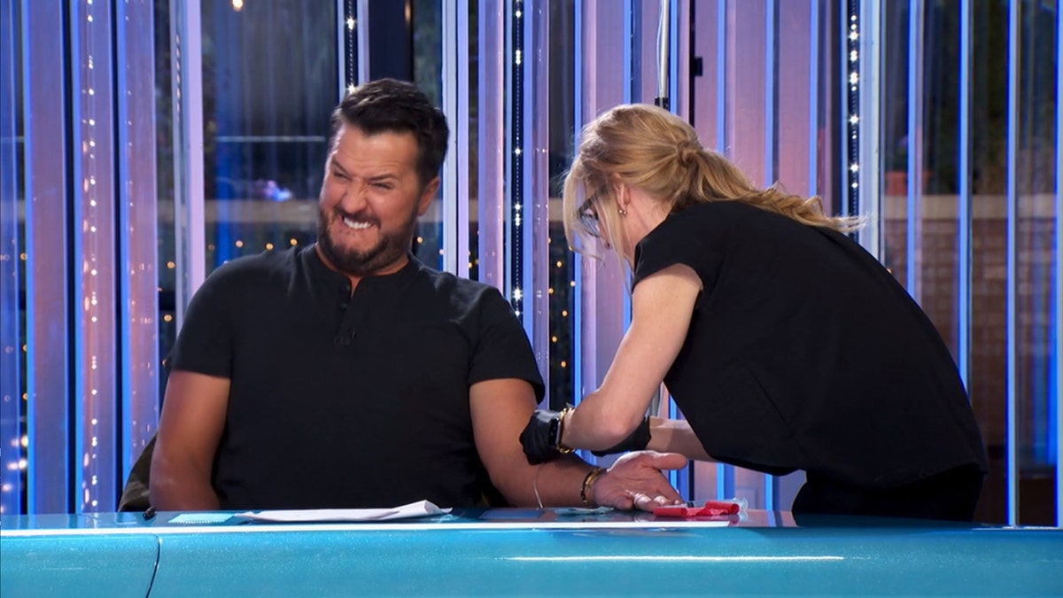 Luke Bryan wincing as an IV is removed on American Idol