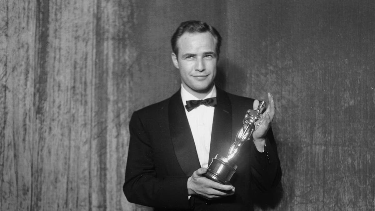 Best actor winner Marlon Brando poses backstage at the 27th Academy Awards holding an Oscar