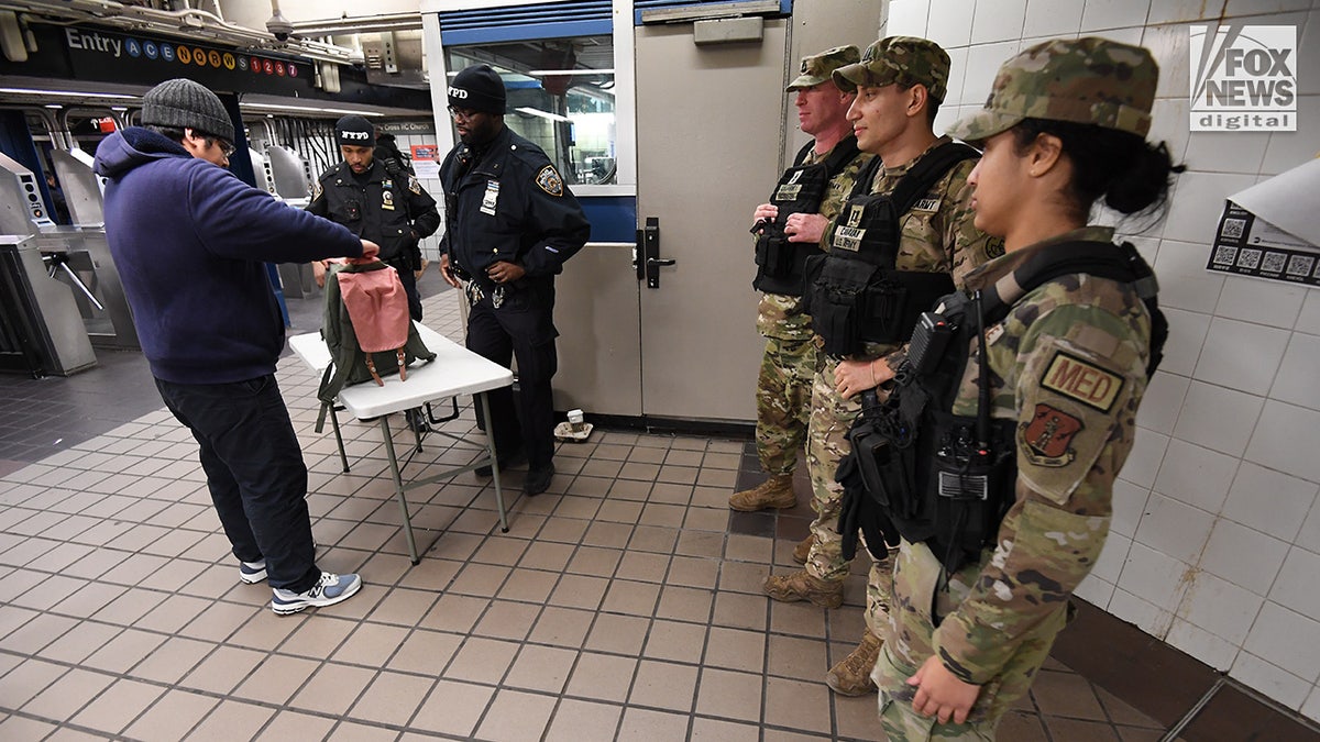 Members of the NYPD and National Guard conduct random bag searches in the New York City subway system
